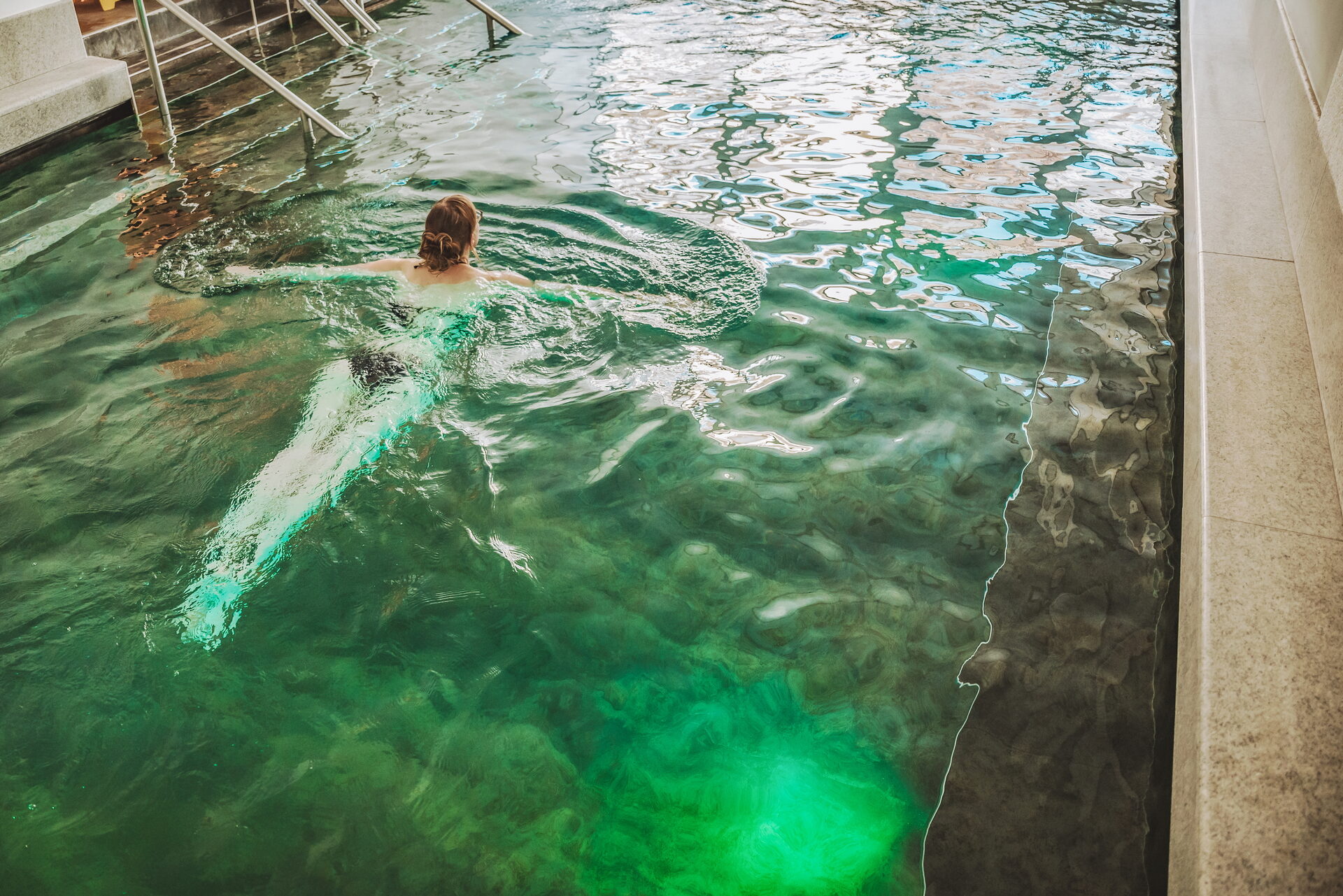 Piscina relax Therme 51° — acqua termale illuminata di verde all'interno